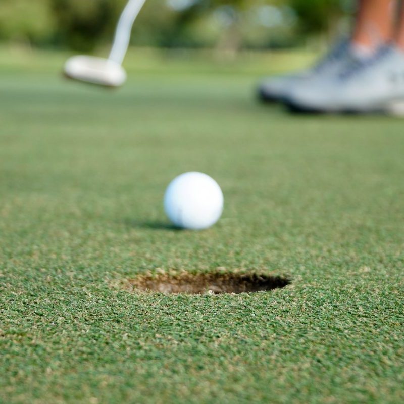 Someone about to sink a shot while golfing