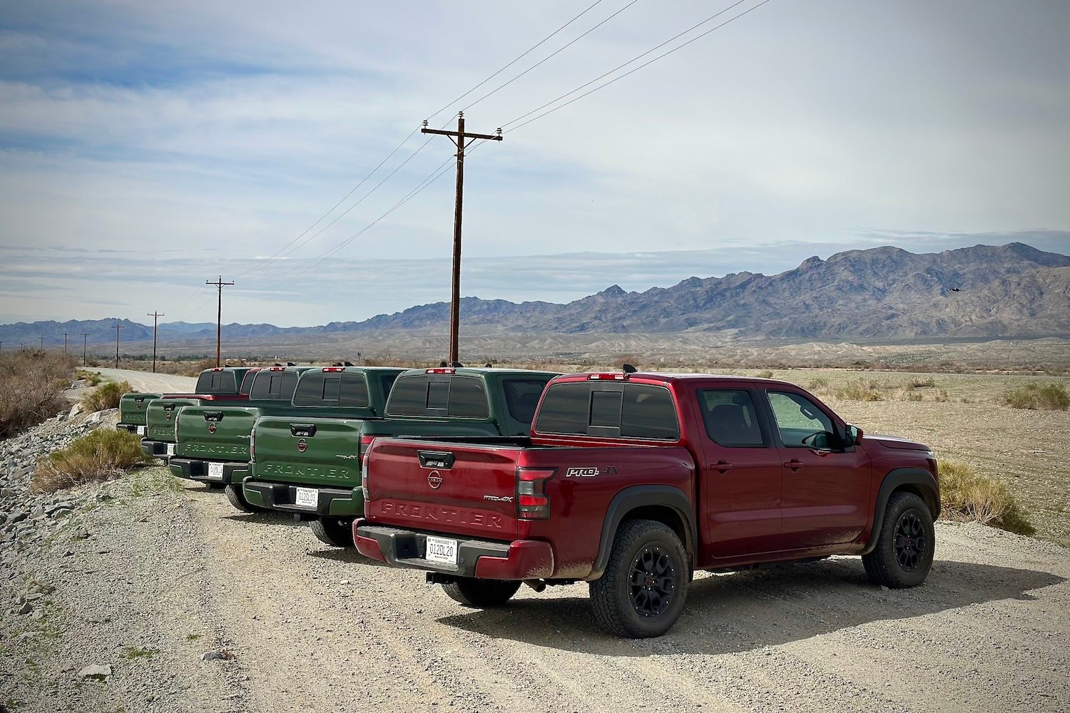 Rear end angle of the 2022 Nissan Frontier Pro-4X parked on a dirt trail in front of mountains.