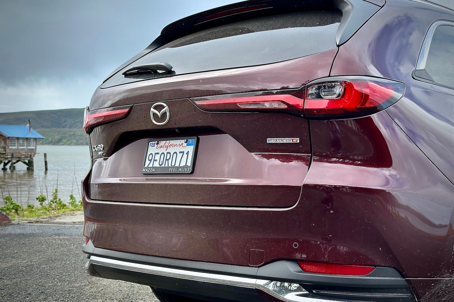 Close up of rear taillights and badges on the 2024 Mazda CX-90 in front of dark skies.
