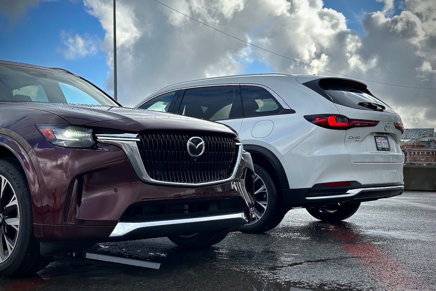 Front and rear end of the 2024 Mazda CX-90 and PHEV parked in front of dark clouds.