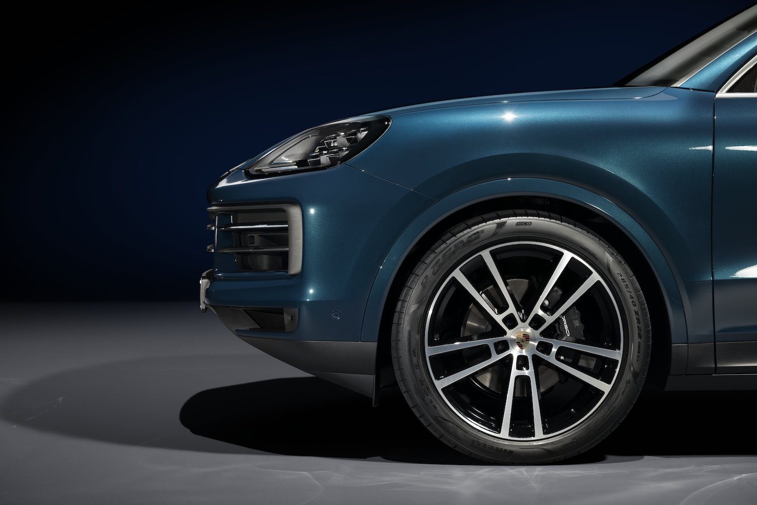 Close up of front end silhouette from the side of 2024 Porsche Cayenne parked in a studio.