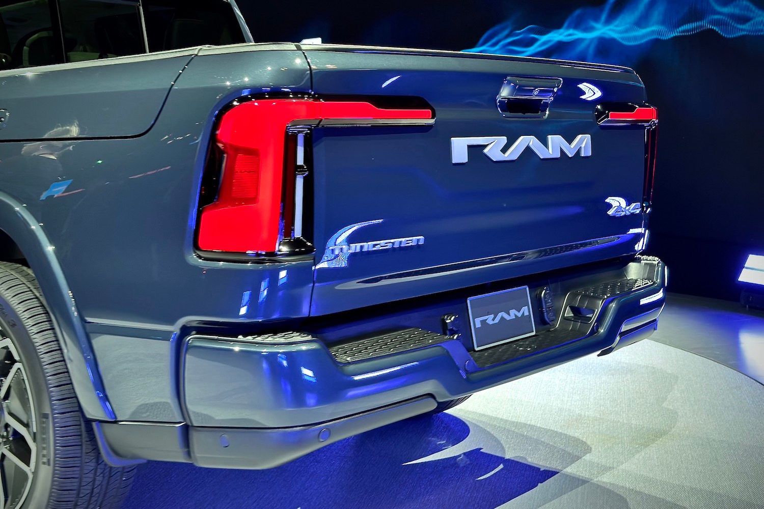 Rear end angle of the 2025 Ram 1500 REV from driver's side parked on a stage.