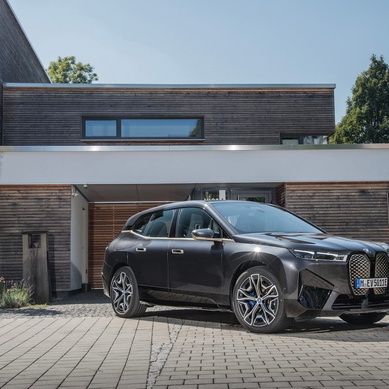 BMW iX xDrive50 front end angle from passenger's side parked in front of a mansion.