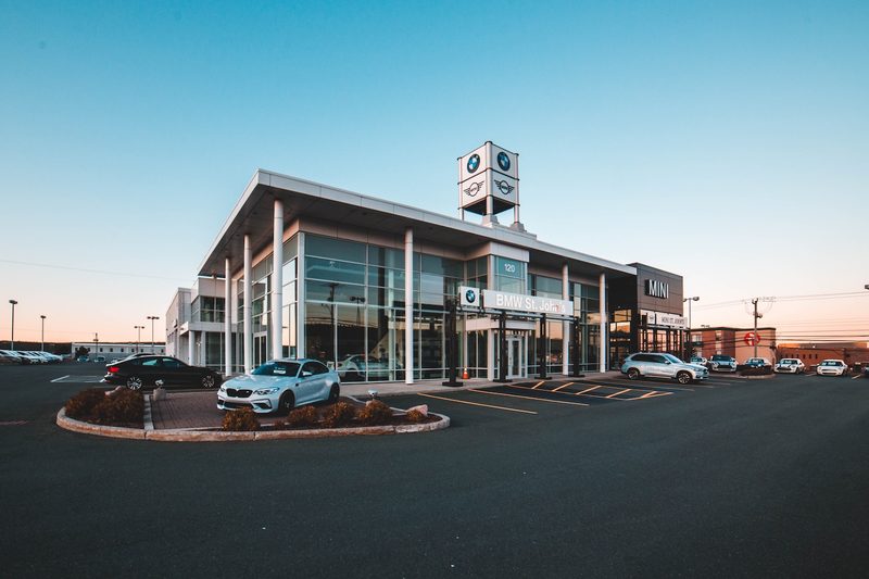 BMW dealership from the outside with car parked outside at sunset.