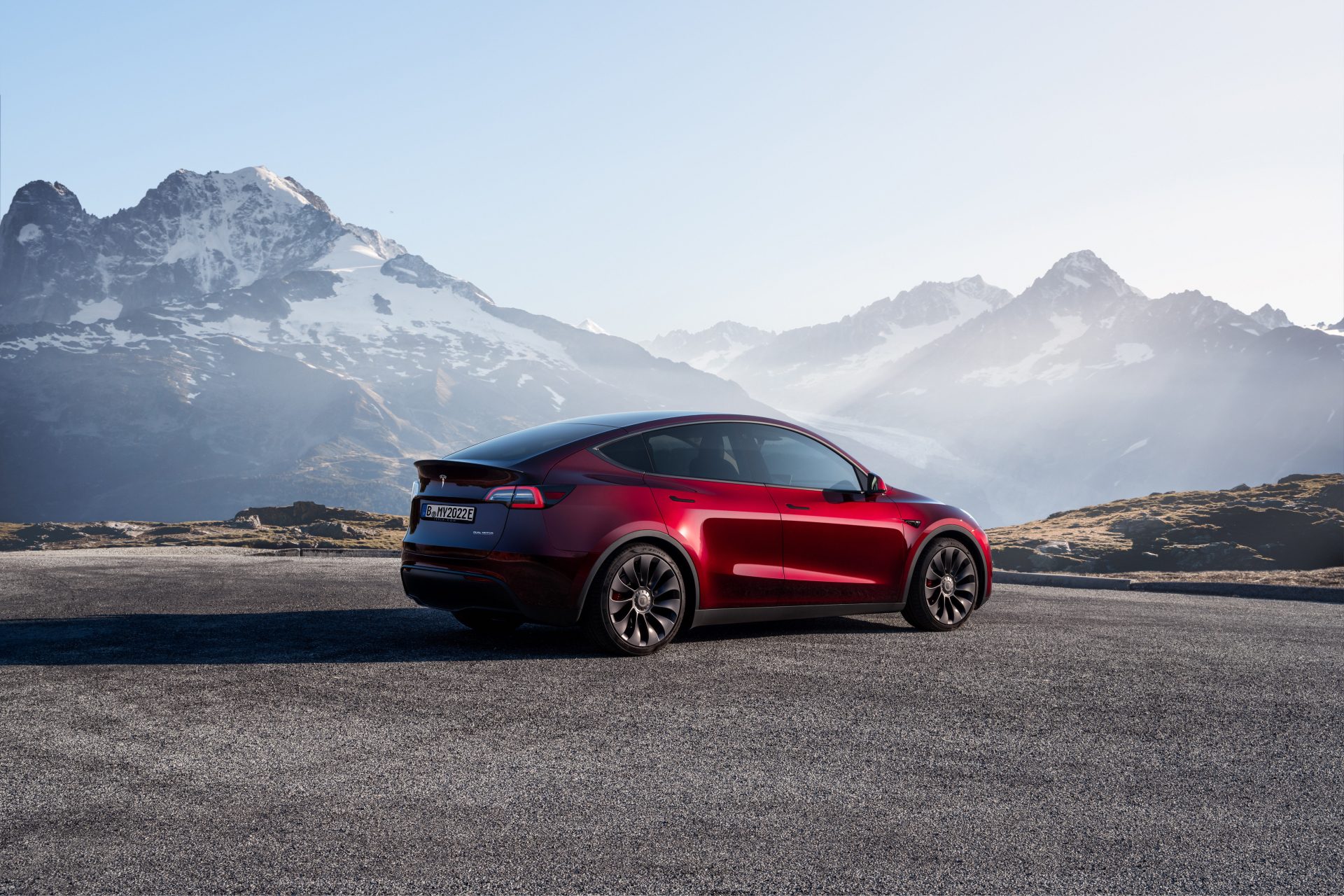 Tesla Model Y rear end angle from passenger side parked in front of mountains.