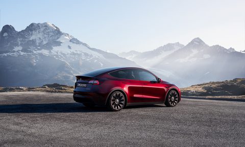Tesla Model Y rear end angle from passenger side parked in front of mountains.