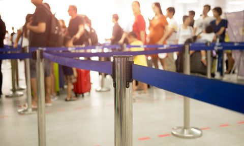 Airport security barriers with long line in background