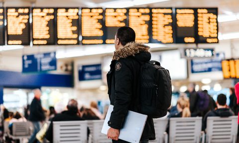 Traveler carrying a laptop checking flight schedule