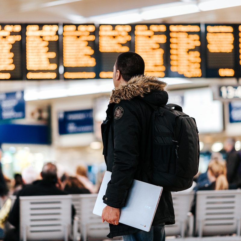 Traveler carrying a laptop checking flight schedule