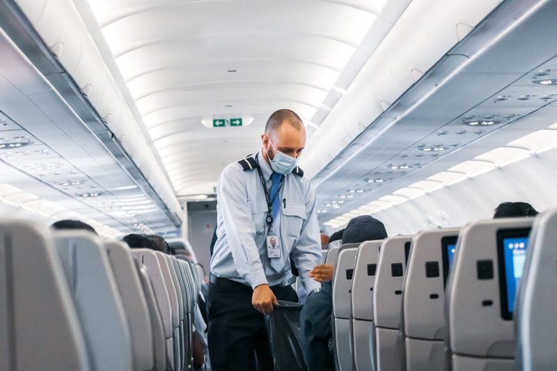 A flight attendant collecting trash from passengers.
