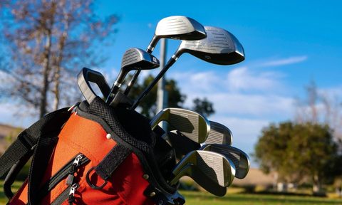 A golf bag with clubs in it out on the golf course.