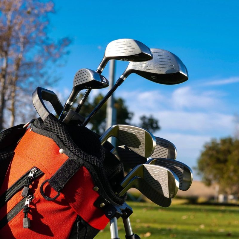 A golf bag with clubs in it out on the golf course.