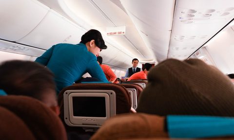 A flight attendant talking to a passenger on a plane.