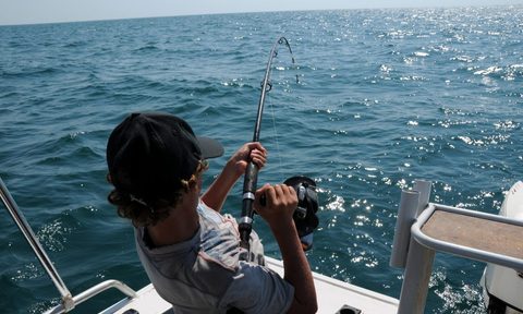 A person out on the ocean fishing, about to reel in a catch.