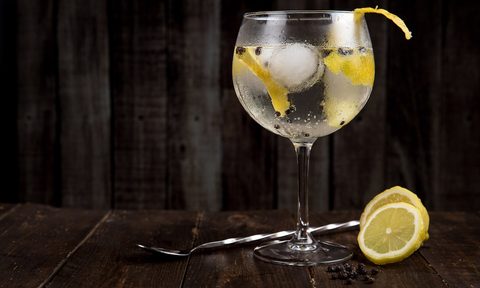 a clear beverage with ice in a glass on dark wooden table