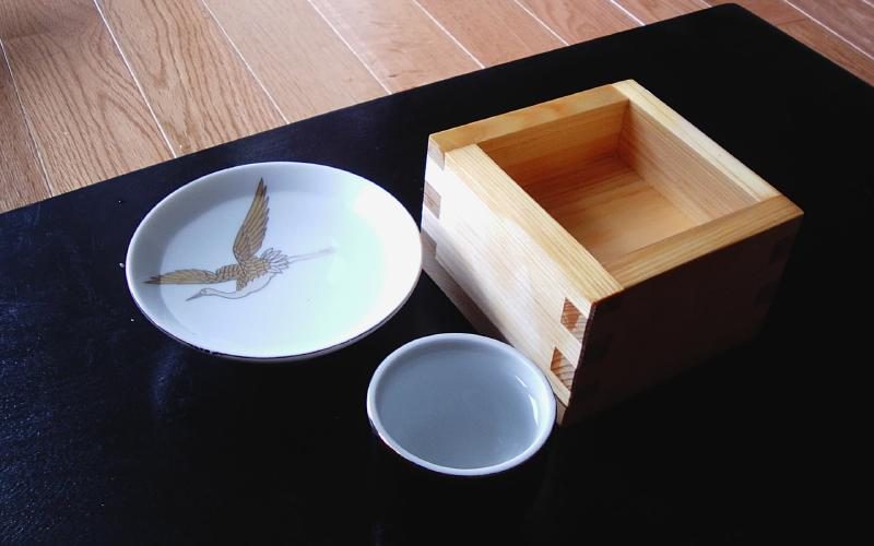 A sake set consisting of a saucer, a small bowl, and a wooden box