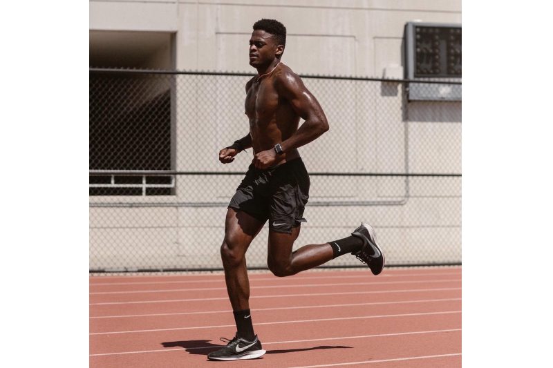 Joe Holder running on an outdoor track, shirtless.