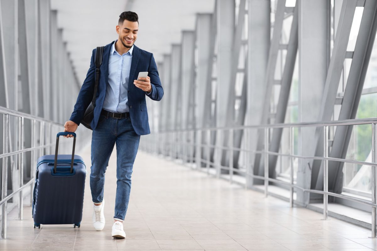Man walking through airport with luggage.