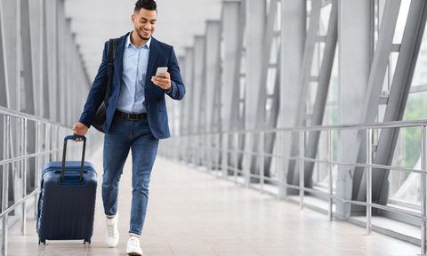 Man walking through airport with luggage.