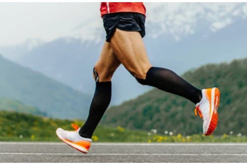 Runner wearing black compression socks while running with a mountain background scene.