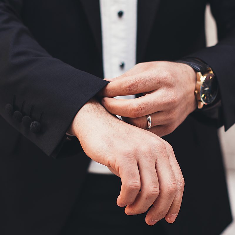 Man in black suit fixing his cuffs