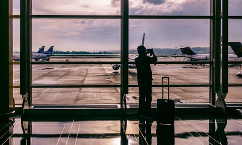 An airport passenger waiting for a flight looking out the window.