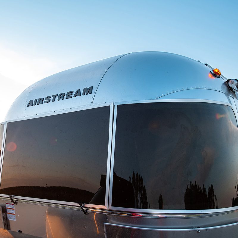 Airstream Caravel travel trailer in front of a lighthouse at sunrise.