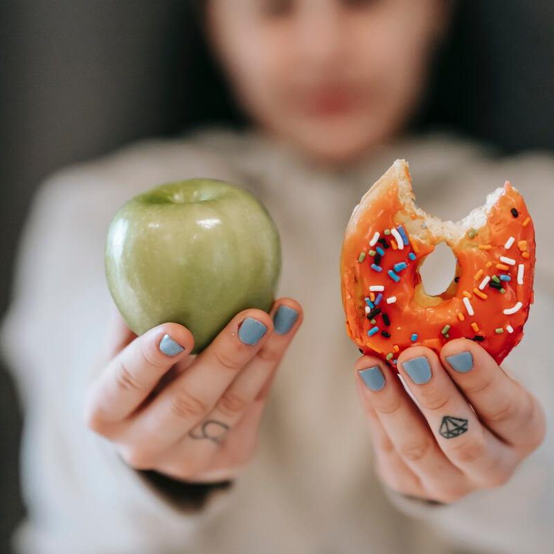 Person holding up an apple and a donut