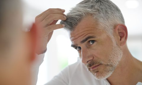 Older man checking out his gray hair