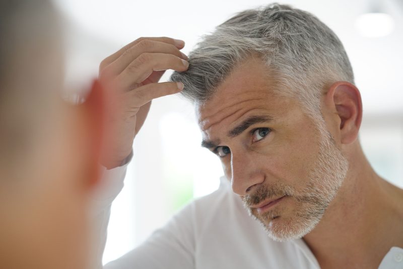 Older man checking out his gray hair