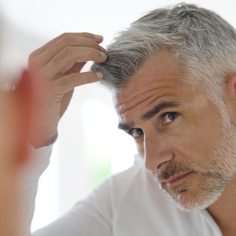 Older man checking out his gray hair