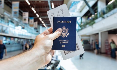 A person holding up their passport in an airport.
