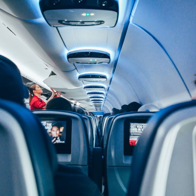 A flight attendant checking on the inside of a cabin on an airplane.