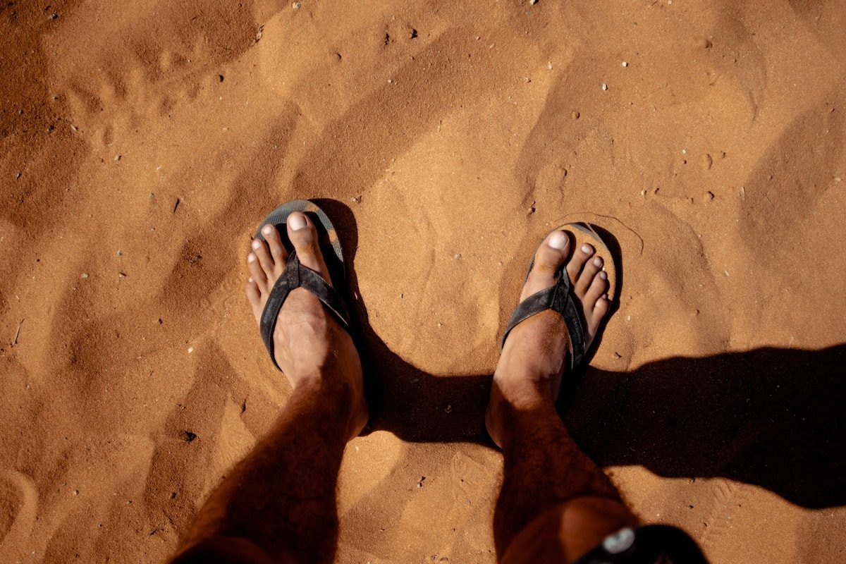 foot in sand flip flops
