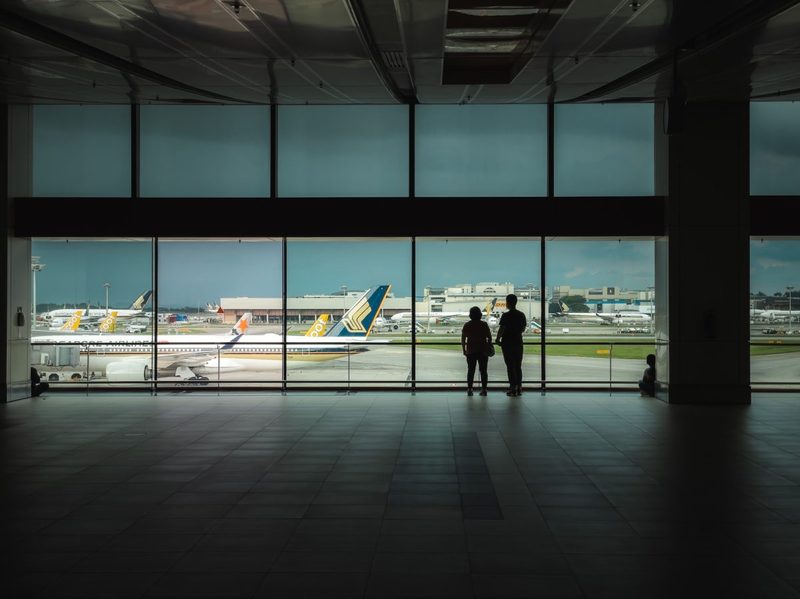 People looking out of an airport window.