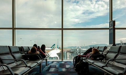 Passengers waiting at the airport, killing time o their phones.