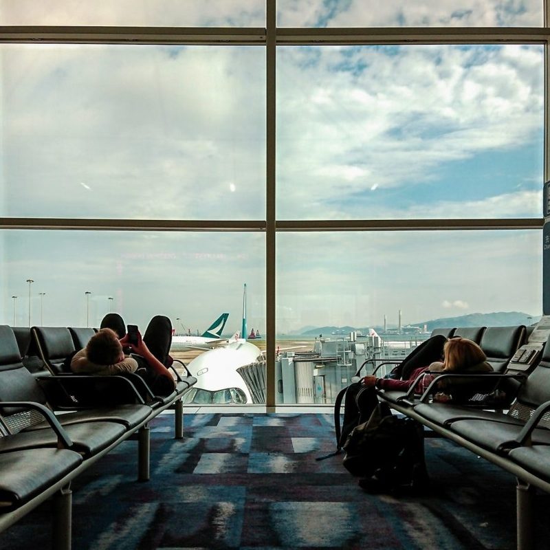Passengers waiting at the airport, killing time o their phones.