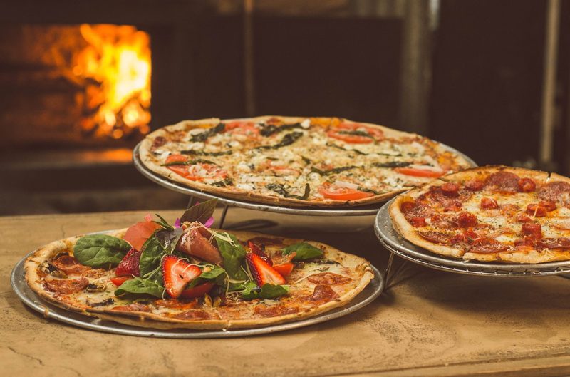 Several pizzas on a wood table