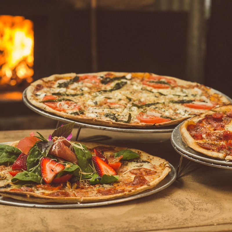 Several pizzas on a wood table