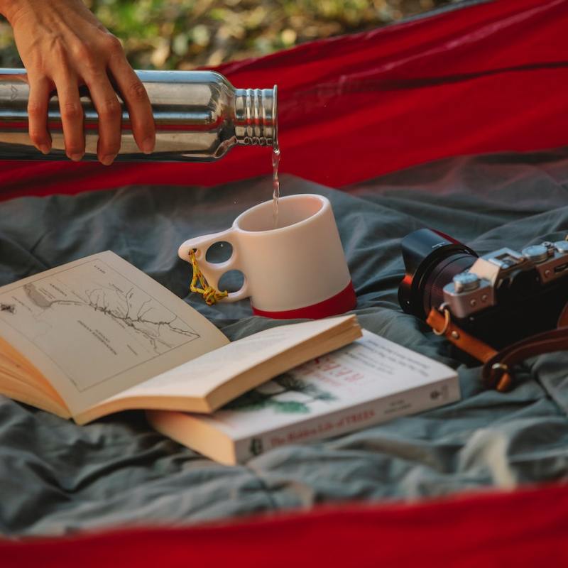 Pouring tea into a mug in a tent beside a book