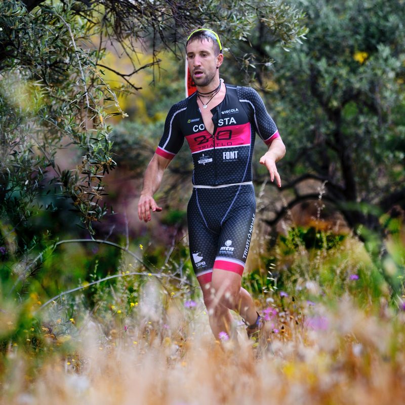 A runner in a running uniform jogging through the woods