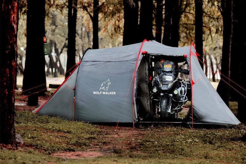 Motorcycle parked inside the Wolf Walker Motorcycle Tent among a stand of trees.