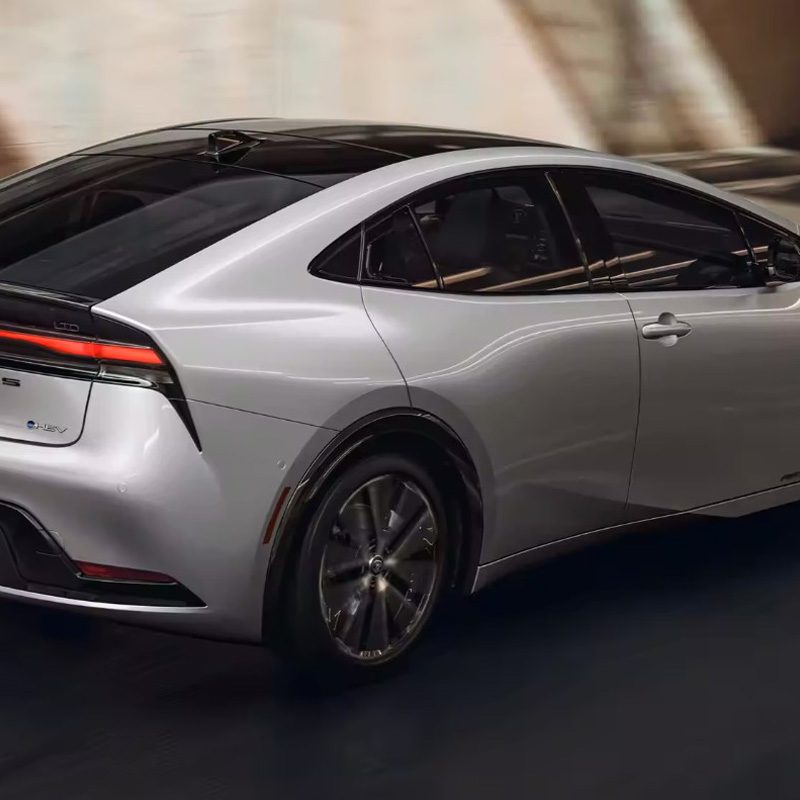 Silver 2023 Toyota Prius driving against a blurred background.