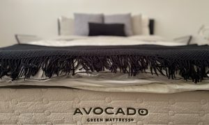 A made bed showing off the Avocado mattress logo.