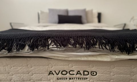A made bed showing off the Avocado mattress logo.
