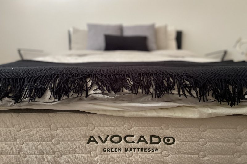 A made bed showing off the Avocado mattress logo.