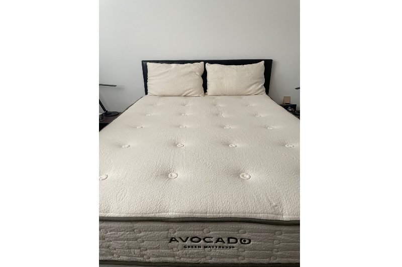 Tall angle shot of the Avocado mattress and pillows on a bed frame.
