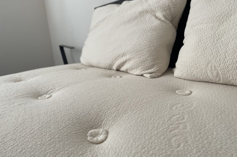 Close up shot of the Avocado mattress showing the hand tufted stitching and pillows.