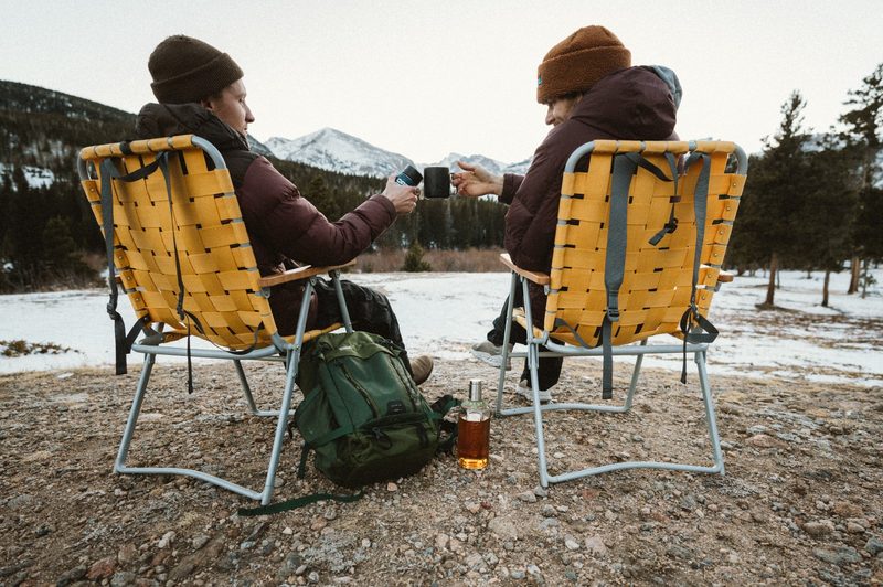A couple of people enjoy a bottle of TINCUP whiskey on a snowy mountain day.