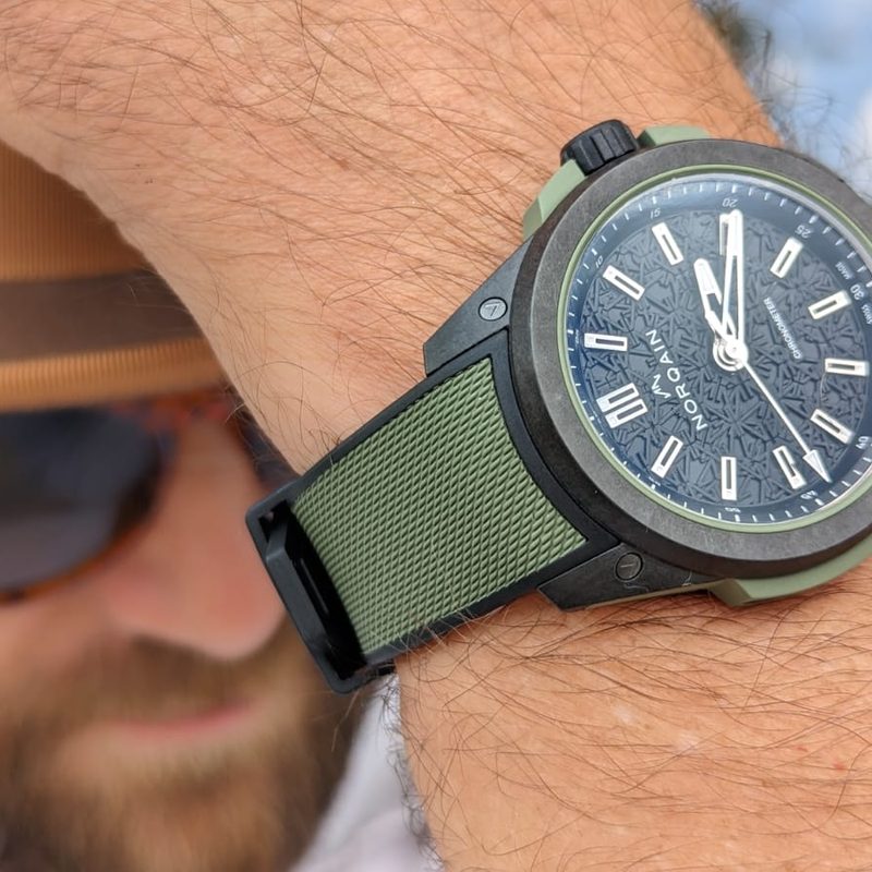 Man wearing Norqain watch and adjusting his hat
